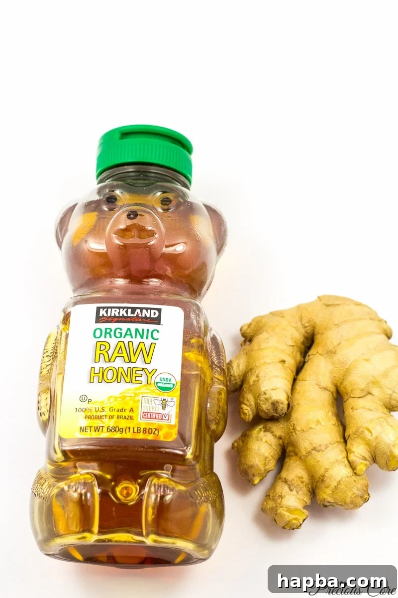 Fresh ginger drink ingredients laid out: raw ginger root, a jar of honey, and water, symbolizing natural and simple components.