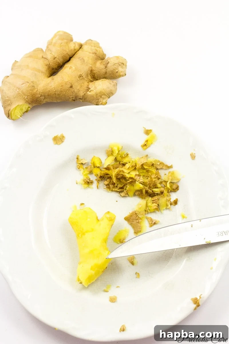Peeled ginger on a white plate, ready for slicing, showing the preparation stage of the drink.