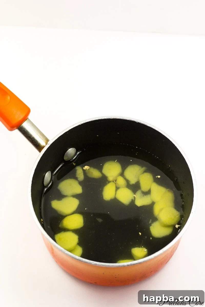 Sliced, peeled ginger placed into a pot with water, illustrating the initial step of brewing the ginger drink.