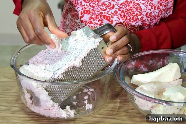Hands grating cocoyams on a box grater, creating the paste for Ekwang.