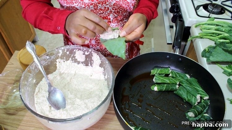 Hands carefully wrapping cocoyam paste in green leaves, preparing the individual Ekwang parcels.
