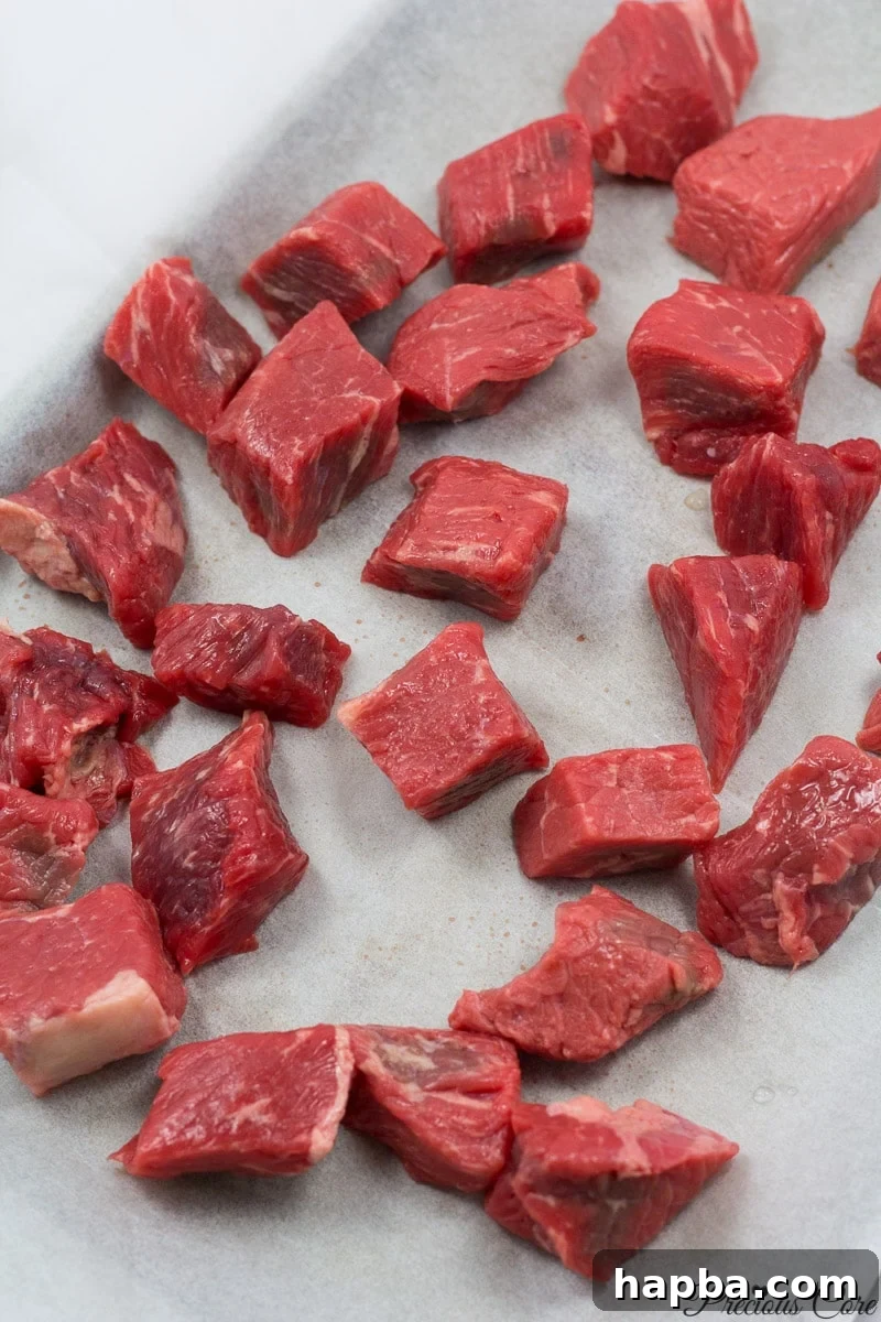 Cubed beef on a lined baking sheet, ready for smoking.