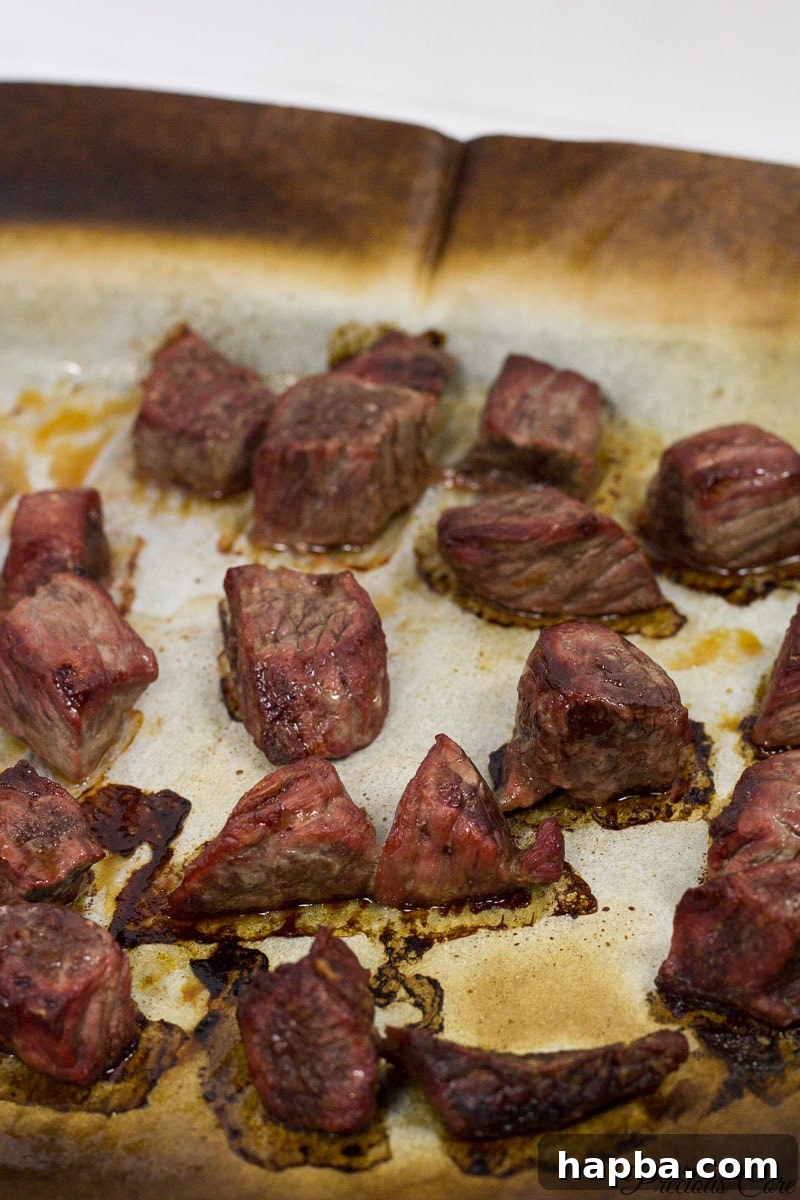 Cooked, smoky meat on a lined baking sheet, ready for use in a meal.