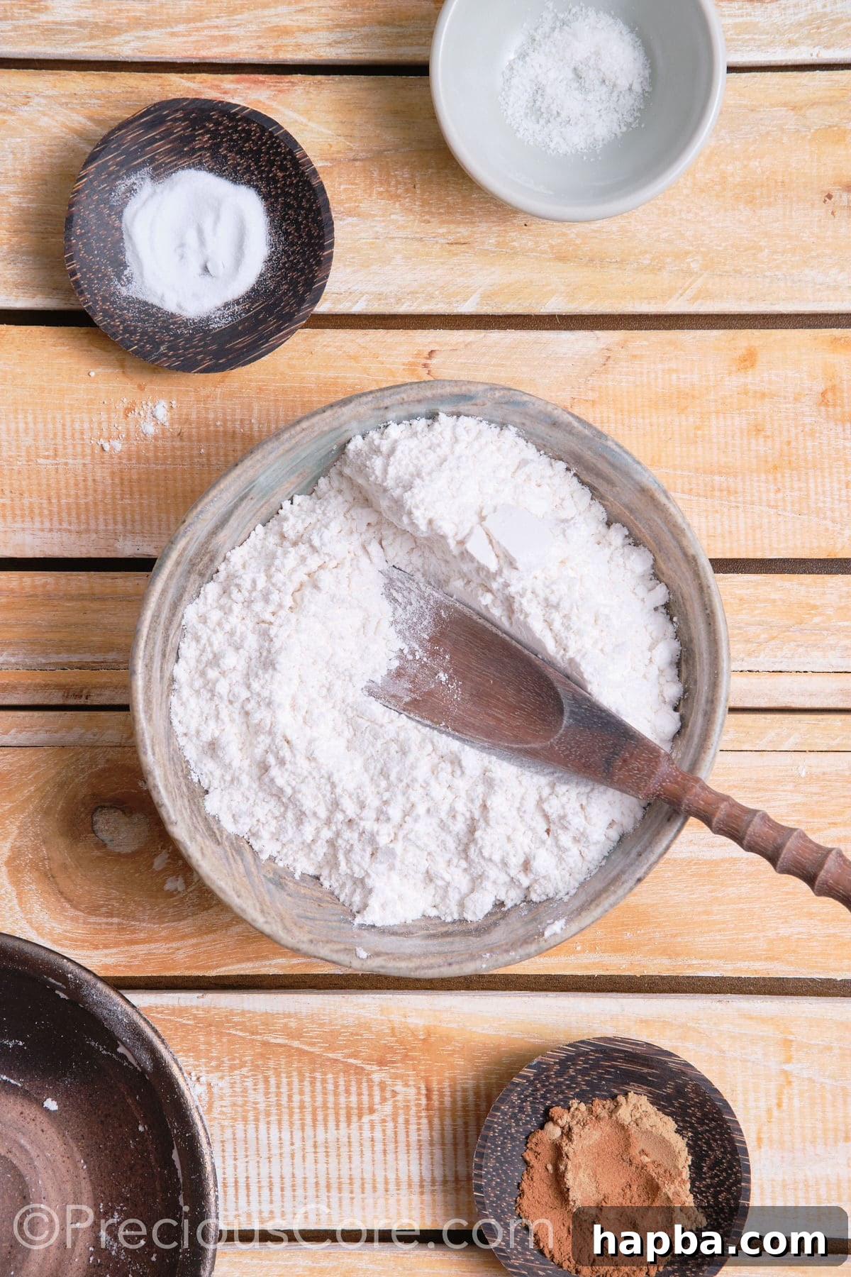 Adding various dry ingredients, including spices, to a bowl for cookie preparation.