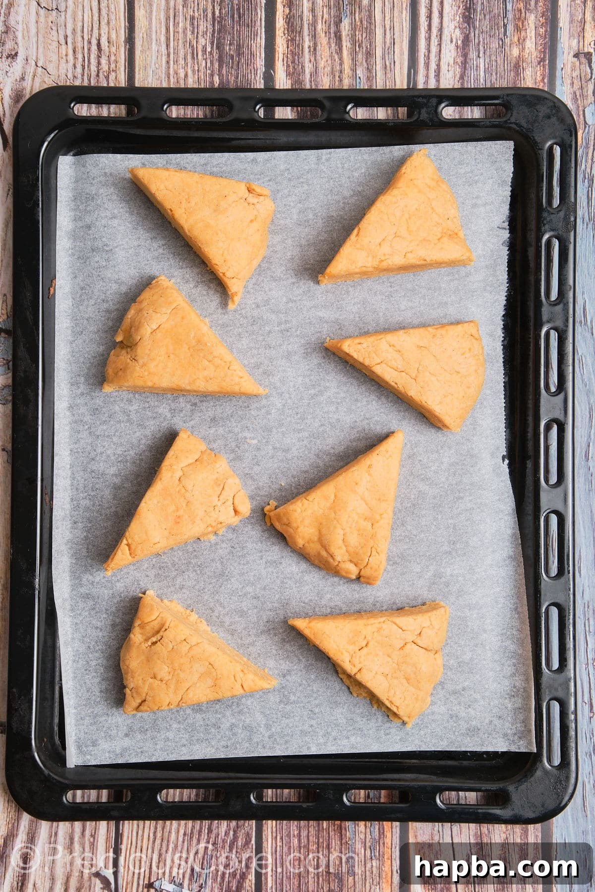 Golden Sweet Potato Scones 14 Unbaked triangular sweet potato scones arranged on a baking sheet lined with parchment paper, ready for freezing.