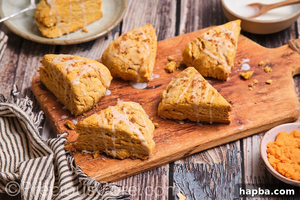 Golden Sweet Potato Scones 3 The most delicious-looking sweet potato scones arranged neatly on a rustic wooden chopping board, highlighting their golden-brown tops.