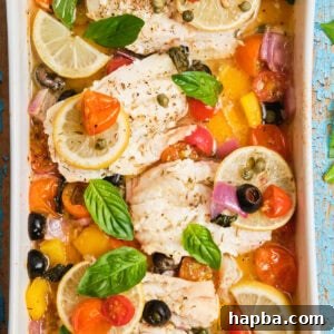 White fish fillets in a casserole dish baked with veggies.