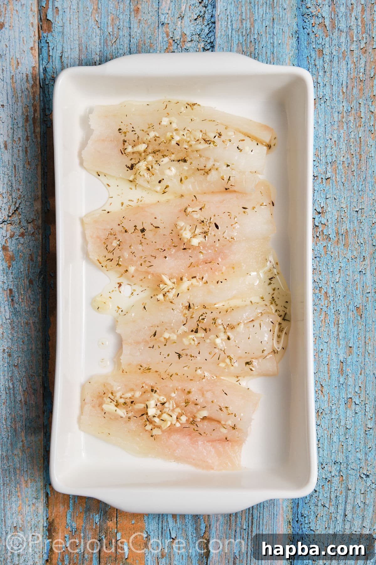 Cod fillets beautifully marinated in a shallow pan, thoroughly coated with the aromatic Mediterranean marinade.