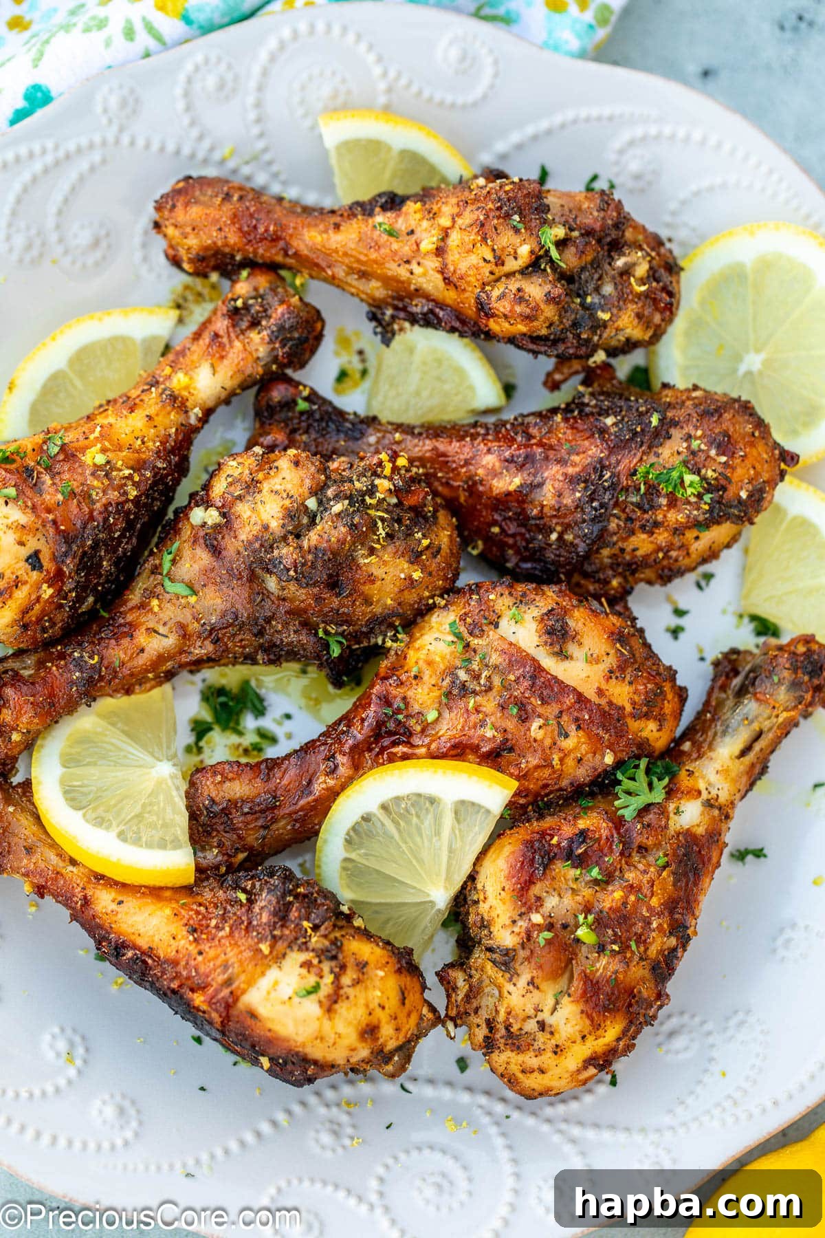 Golden Lemon Pepper Drumsticks 2 Cooked lemon pepper drumsticks on a white plate, garnished with fresh parsley and lemon slices.