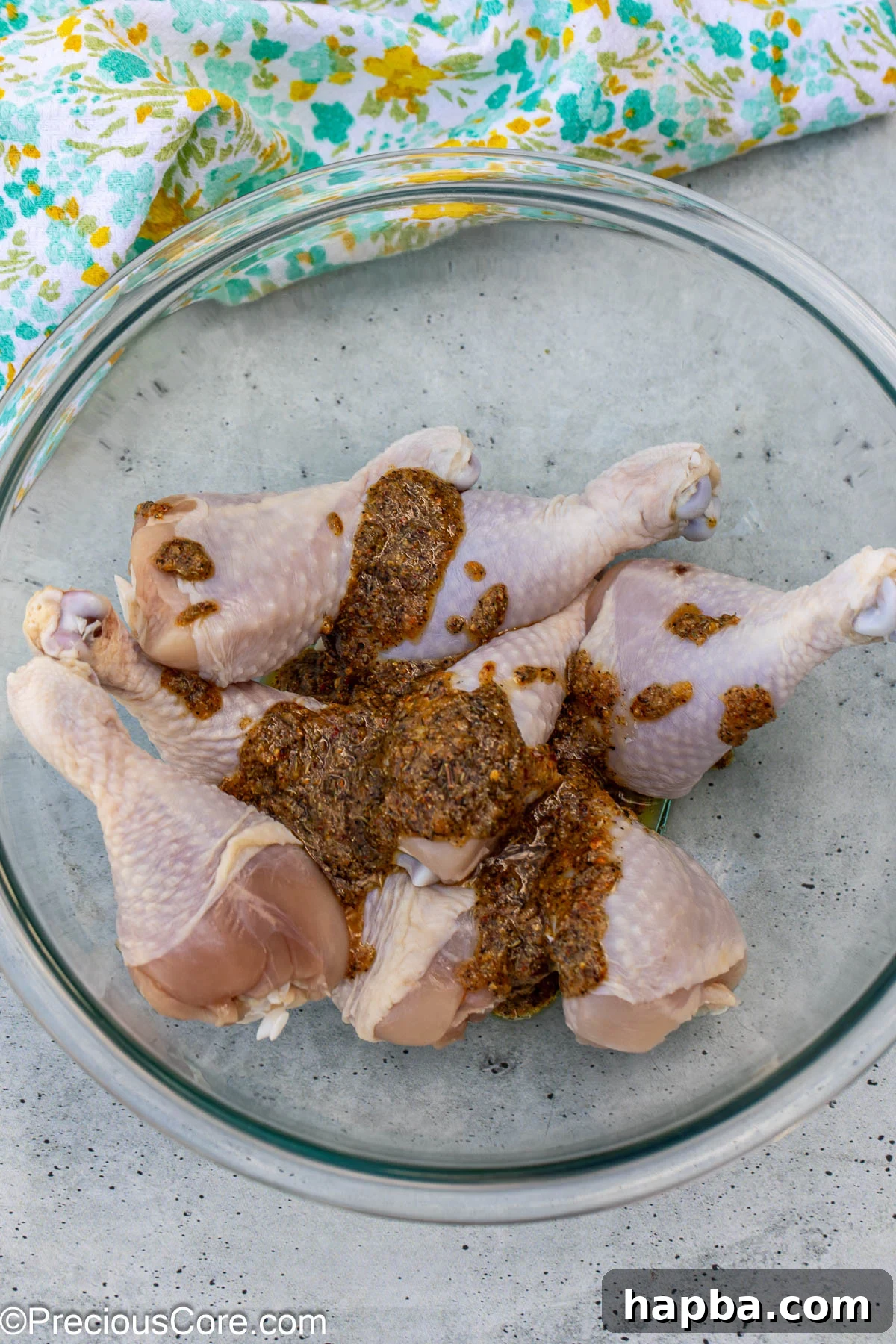 Golden Lemon Pepper Drumsticks 6 Marinade being poured over raw chicken drumsticks in a mixing bowl.