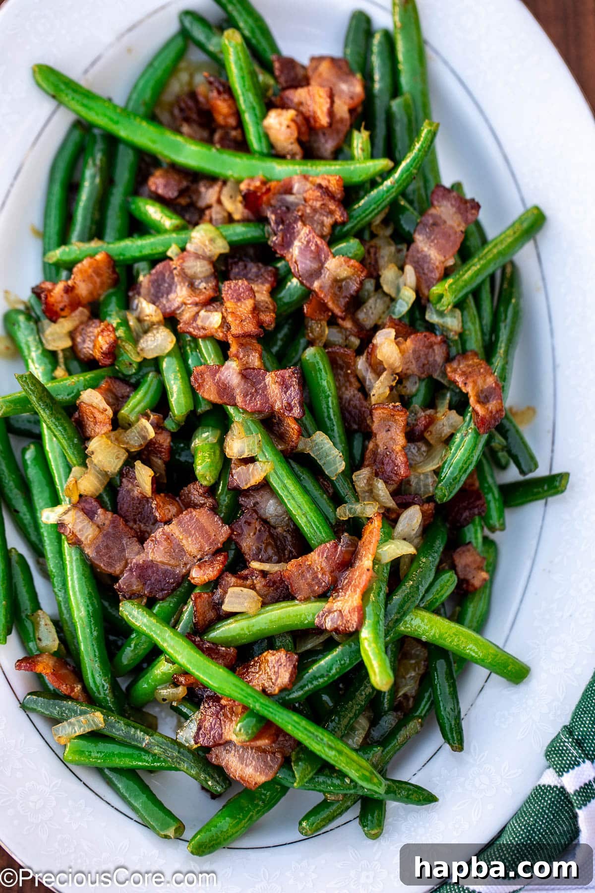 Bacon and green beans on a white tray, showcasing their vibrant colors and crispy texture.