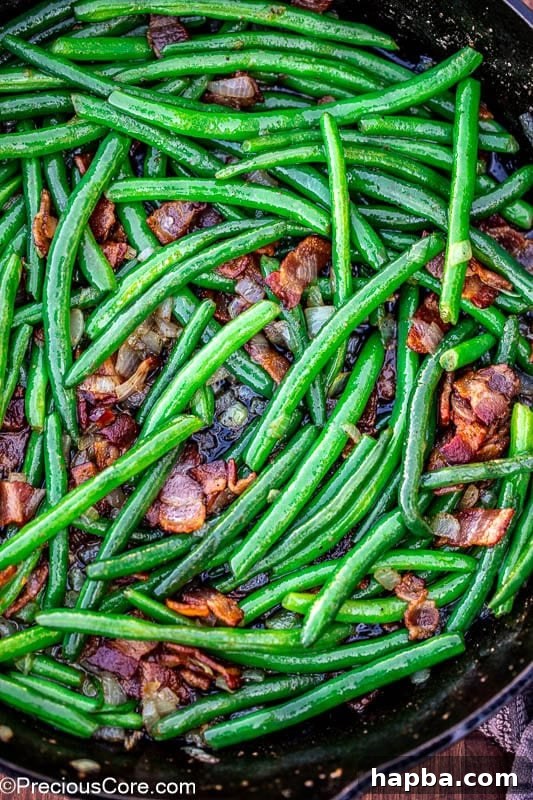A pan full of perfectly cooked green beans with bacon, ready to be served.