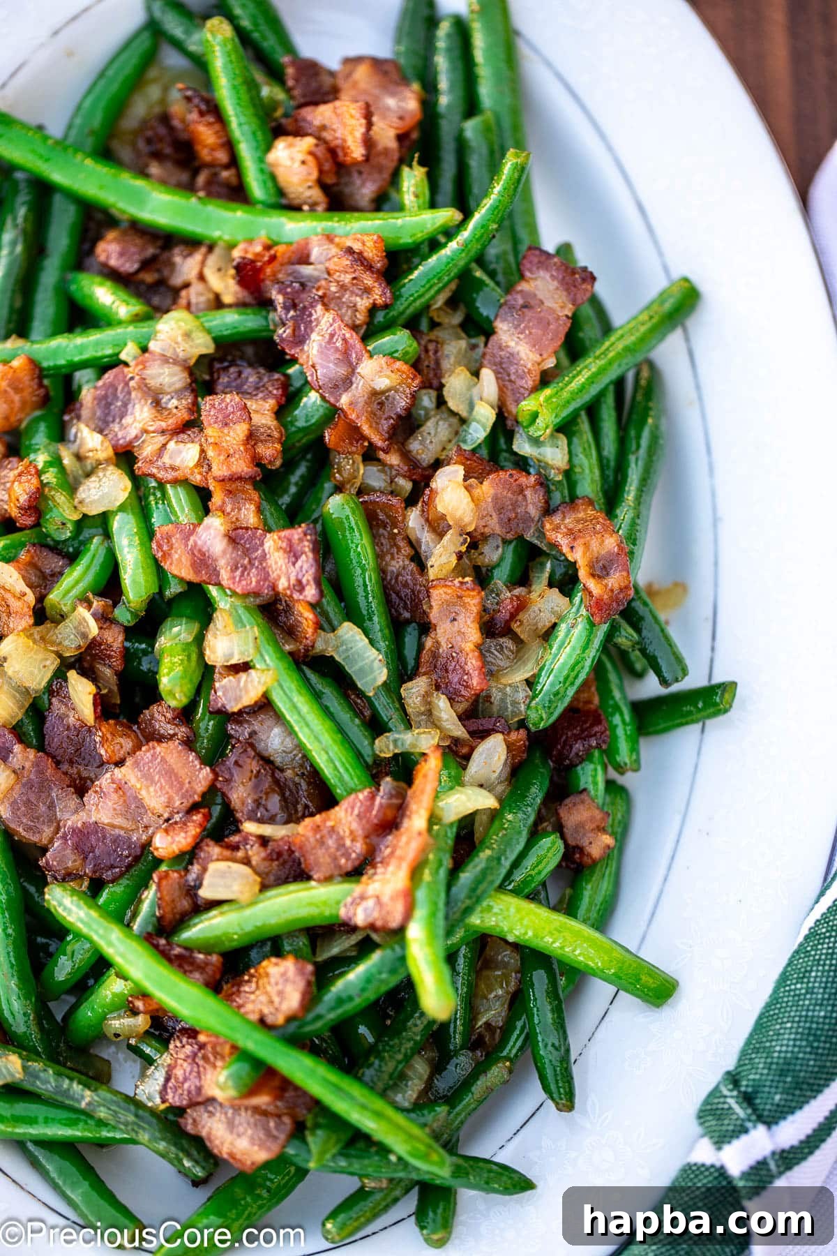 Bright colored green beans and crispy bacon artfully arranged on a serving tray.