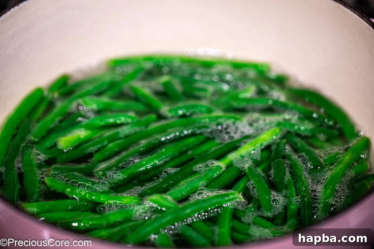 Fresh green beans being blanched in a pot of boiling water.