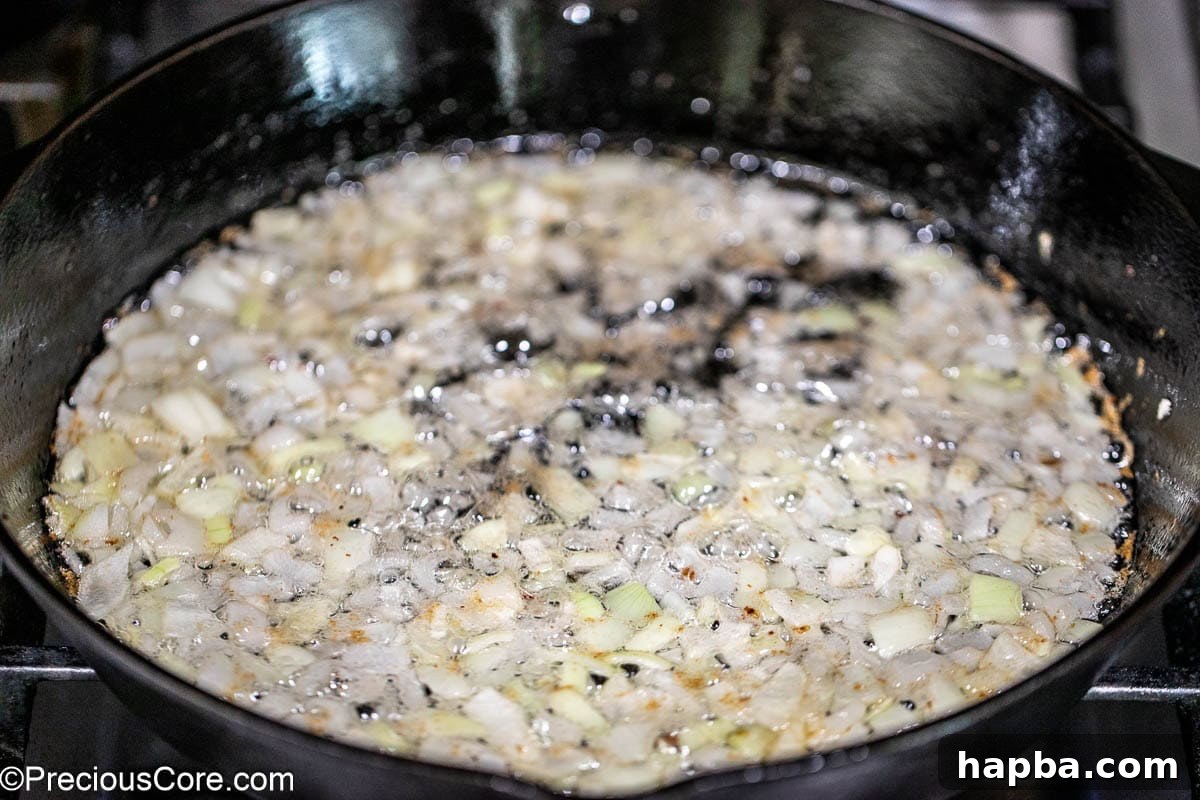 Diced onions sautéing in the cast iron skillet with bacon drippings.