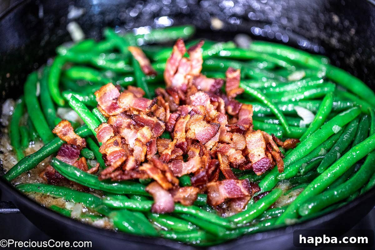Crispy bacon bits sprinkled over the green beans in the skillet.