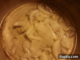 Tomatoes frying in a pan with onions and oil, reducing and concentrating their flavor.