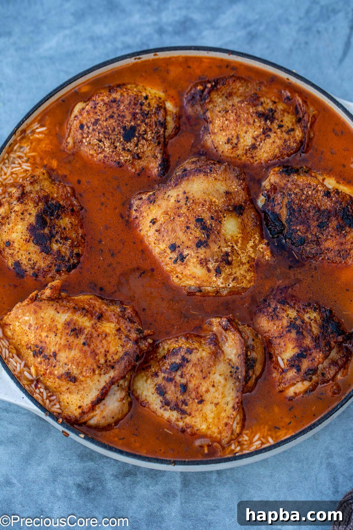 chicken thighs placed in a pot with rice and stock.