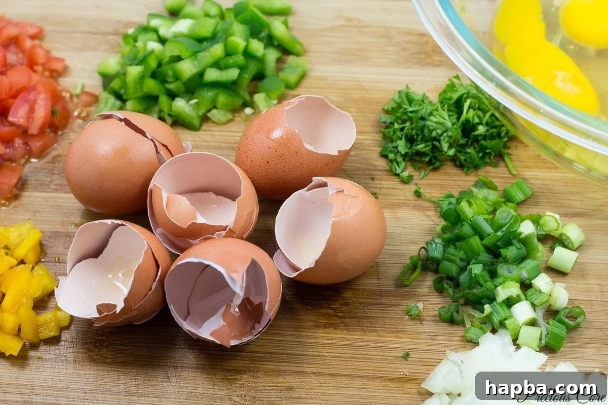 Quick and Healthy Egg Cups 2 Ingredients for breakfast egg muffins laid out on a counter, including eggs, chopped bell peppers, onions, tomatoes, and parsley.