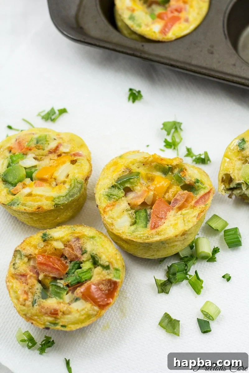 Quick and Healthy Egg Cups 5 A single breakfast egg muffin on a white plate with a fork, ready to be eaten.