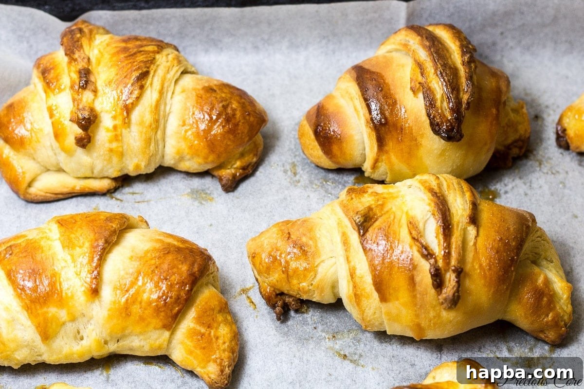 Friday Feast 2 Freshly baked homemade croissants cooling on parchment paper, showcasing their golden-brown, flaky exterior and artisan quality. A symbol of culinary achievement and the joy of baking.