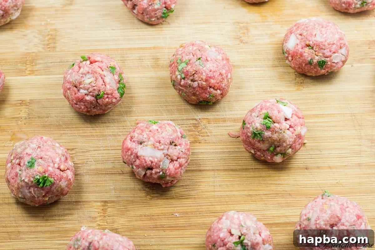 African Spiced Meatballs 7 Raw meatballs neatly arranged on a wooden cutting board, ready for frying.