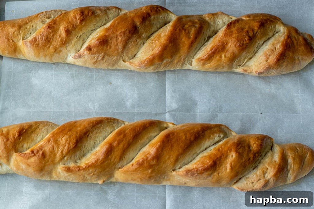 Freshly baked homemade French bread cooling on a baking sheet, showcasing its perfectly golden crust