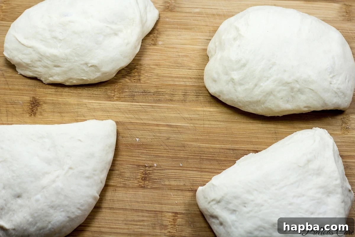 French bread dough cut into four equal pieces, prepared for shaping into loaves