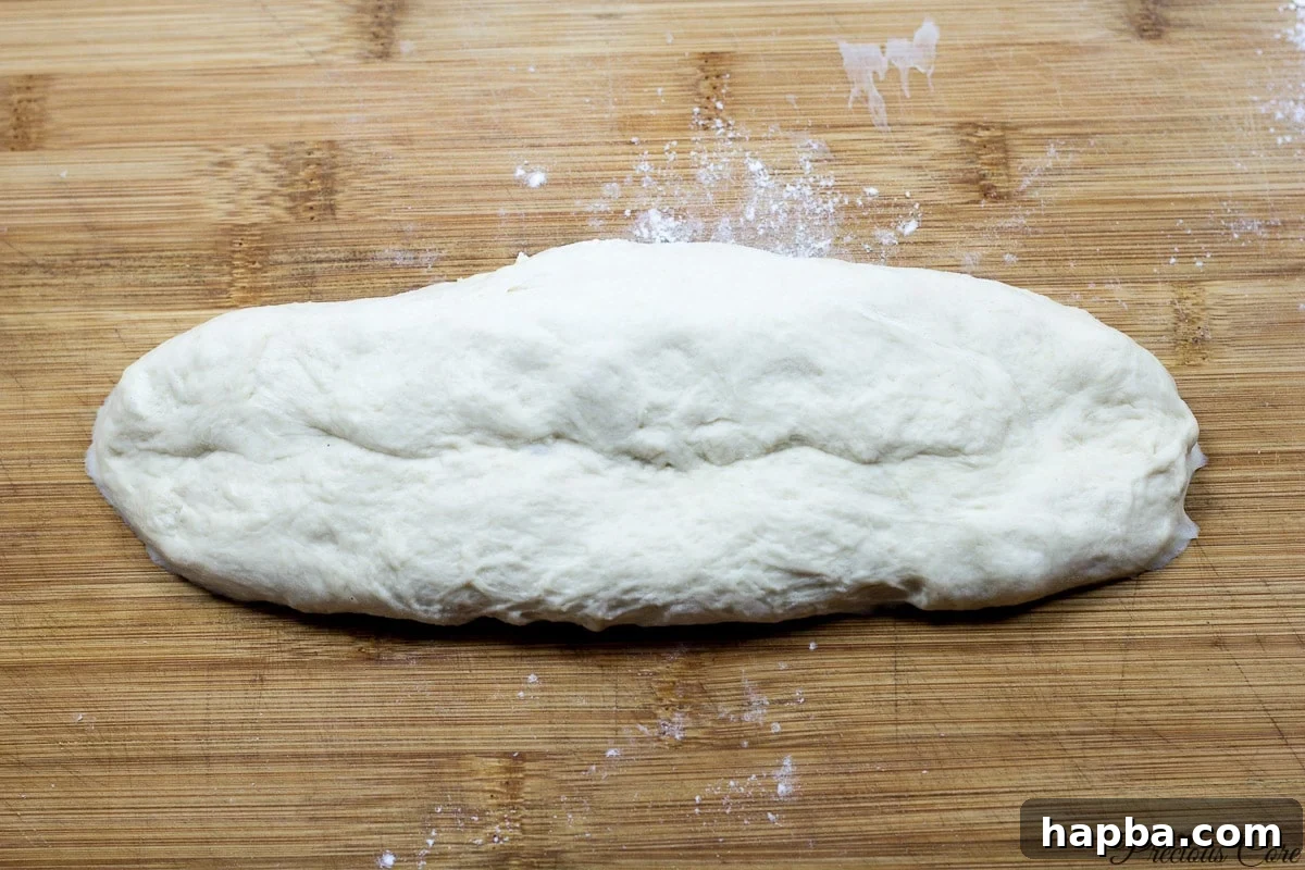 One piece of French bread dough shaped into a log, demonstrating the shaping technique