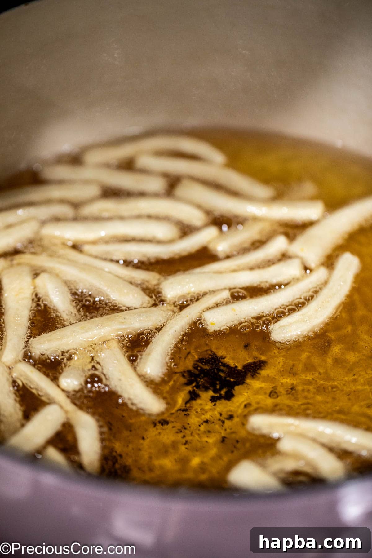 Chin Chin dough strips gently frying in hot oil, turning golden.