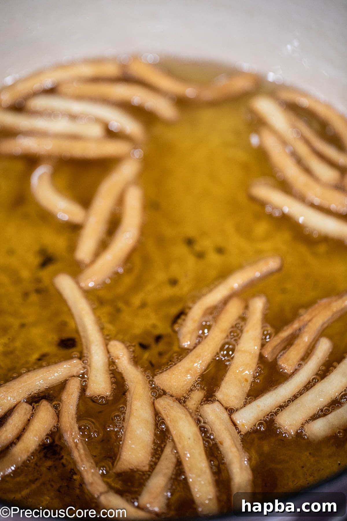 Finished golden-brown Chin Chin pieces submerged in frying oil.