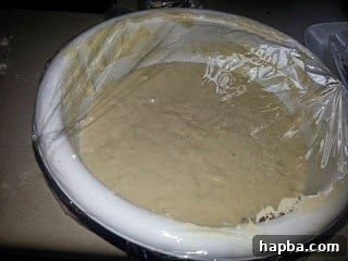 Puff-puff dough covered with plastic wrap, ready for proofing in a warm place.