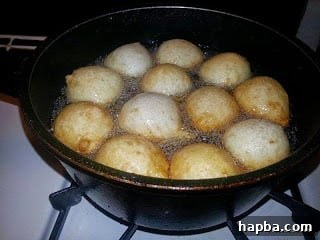 Puff-puff dough frying in hot oil, bubbling and beginning to turn golden brown.