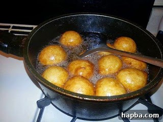 Puff-puff being flipped in hot oil to ensure even browning on all sides.