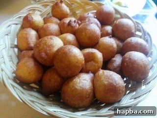 A freshly fried batch of golden brown puff-puff resting on paper towels to drain excess oil.