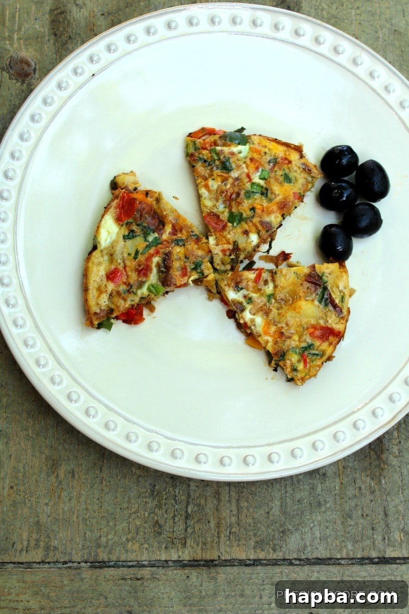 A colorful frittata slice served on a plate with olives.