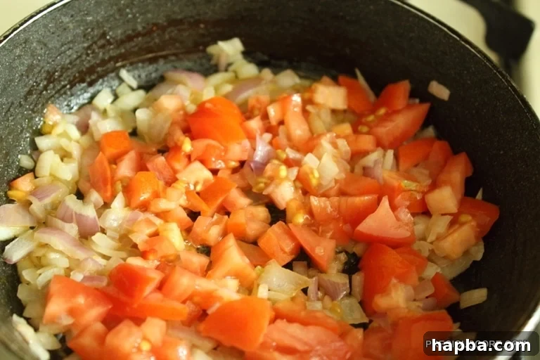Chopped tomatoes added to the skillet with onions.