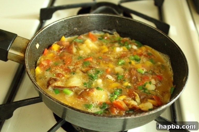 Egg mixture poured over the vegetables in the skillet.
