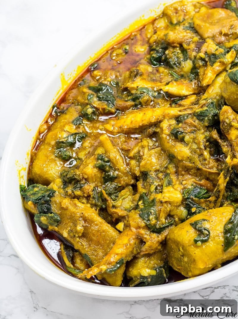 African plantain porridge recipe, showing the rich red color from palm oil and leafy greens.