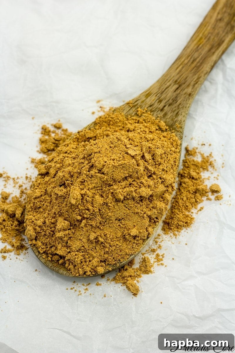 A wooden spoon filled with vibrant homemade Suya spice blend.
