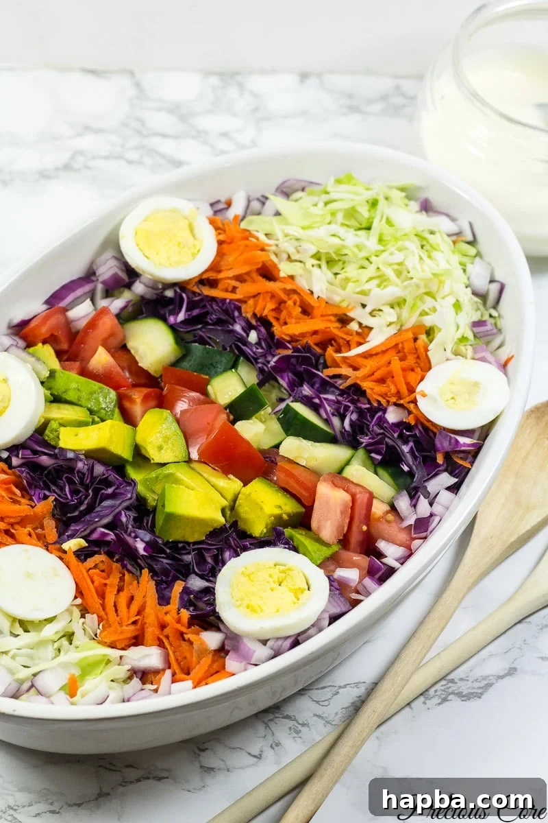 Cameroon salad featuring a colorful array of hard-boiled eggs, red onion, cucumber, cabbage, carrots, and tomatoes, all ready to be dressed.