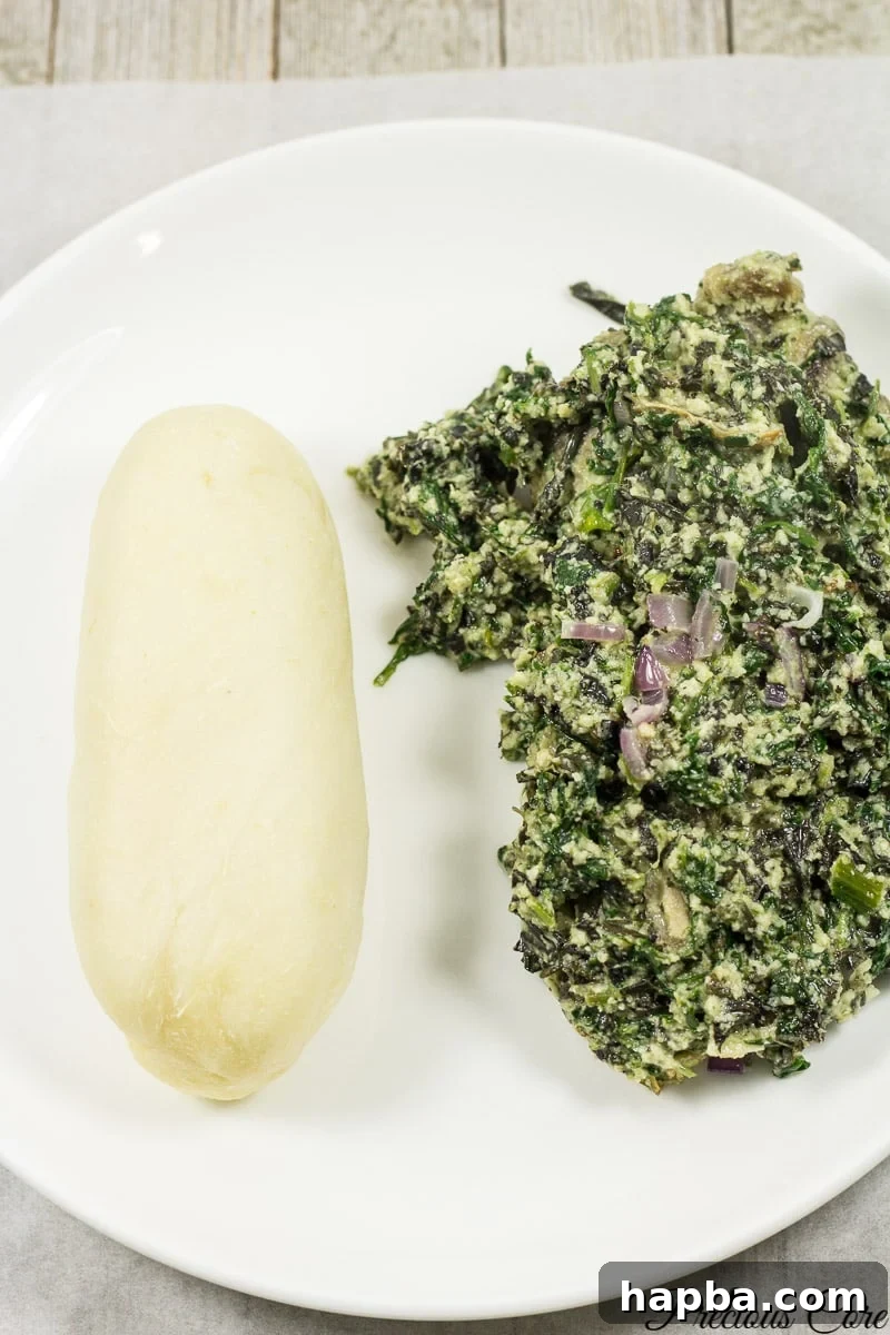 A vibrant platter featuring soft Water Fufu alongside a generous serving of Ndole, a popular Cameroonian bitter leaf stew, showcasing a perfect meal pairing.