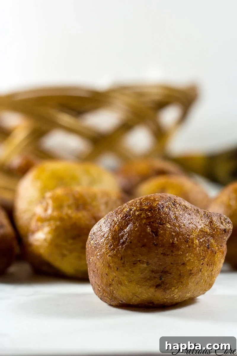 Golden Plantain Puff Puff 2 Golden brown plantain puff puffs piled high on a white plate, ready to be enjoyed.
