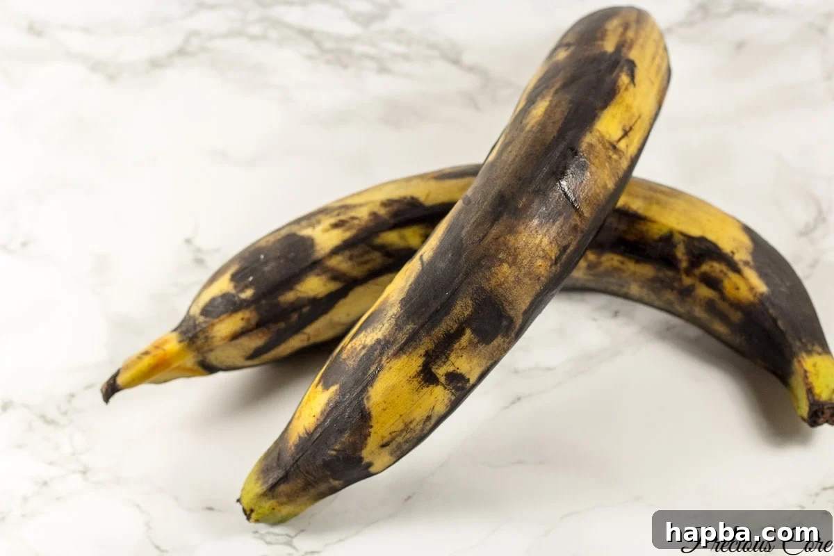 Golden Plantain Puff Puff 5 Several very brown, overripe plantains resting on a elegant marbled countertop, emphasizing their ideal state for this recipe.