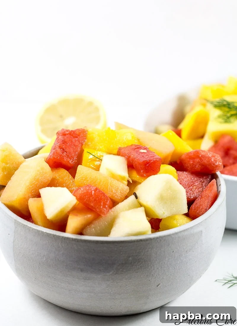 Authentic Cameroonian Fruit Salad Tutorial 3 Close-up shot of a colorful bowl of fruit salad, featuring meticulously diced watermelon, succulent chunks of ripe mango, and other fresh fruit pieces, artfully arranged and ready to be enjoyed.