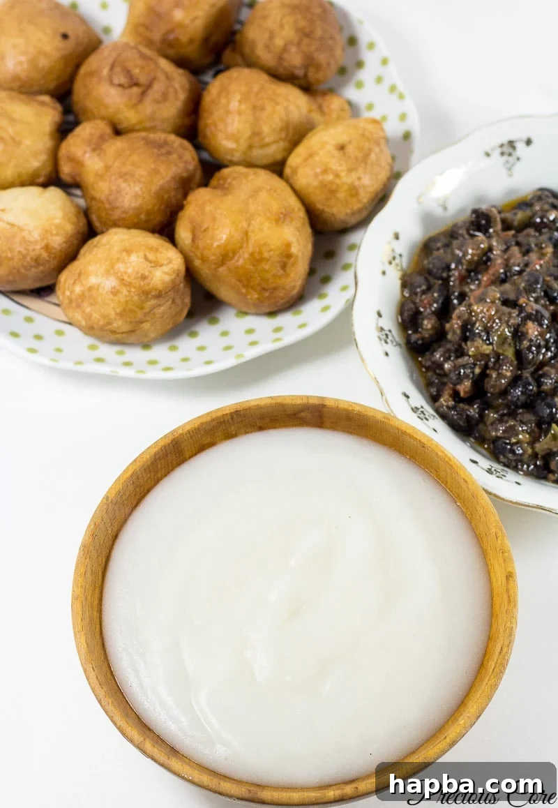 A vibrant West African breakfast spread featuring Pap, served alongside crispy Puff Puff and rich bean stew, embodying a balanced morning meal.