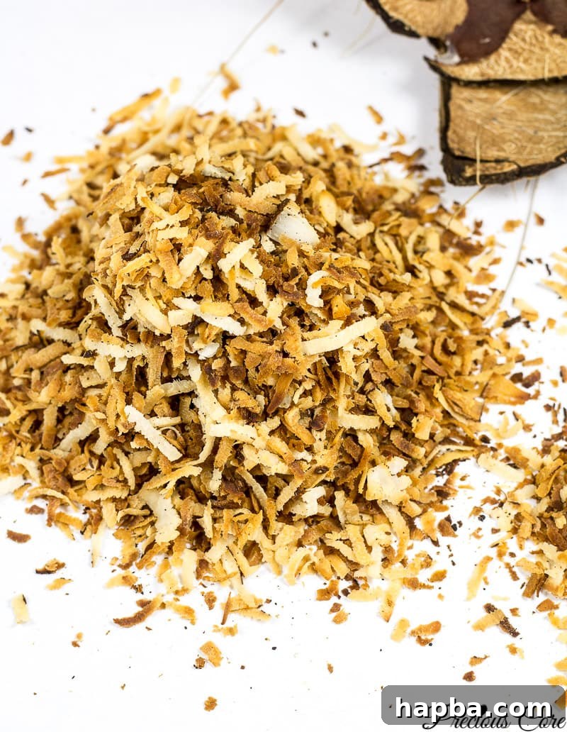 Golden-brown toasted coconut flakes scattered on a clean white surface, highlighting their crispy texture.