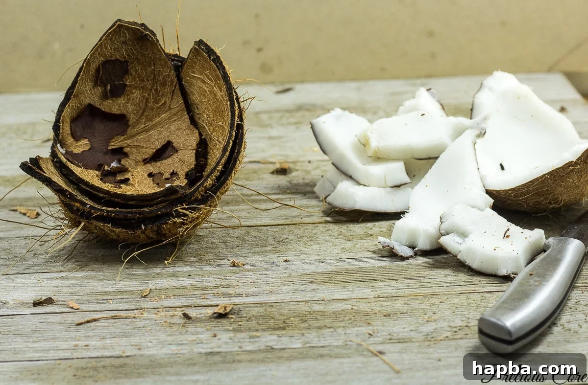 Coconut halves after being microwaved, showing how easily the flesh separates from the shell with a pairing knife.