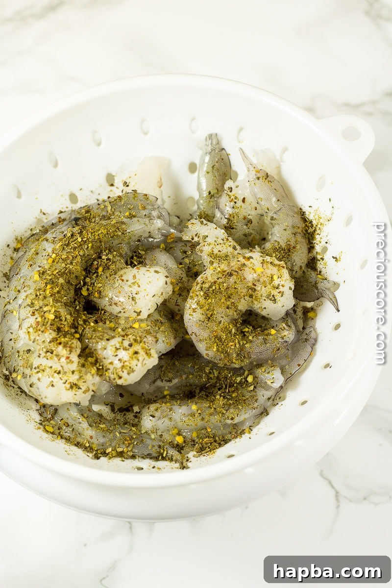 Close-up of raw shrimp generously coated with McCormick Basil, Oregano, Garlic & Sea Salt All Purpose Seasoning.