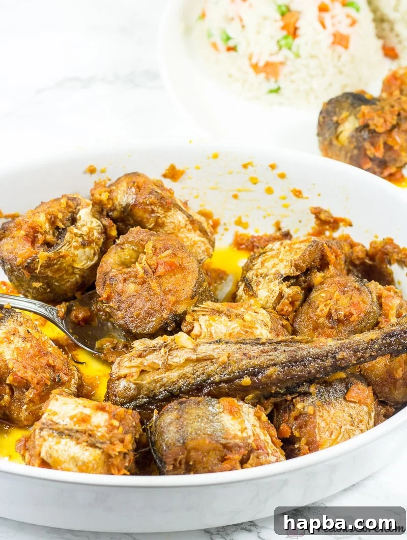 Sweet Heat Fish 2 A beautifully plated dish of Nigerian Peppered Fish, rich with a sweet and spicy red sauce, garnished and ready to be enjoyed.